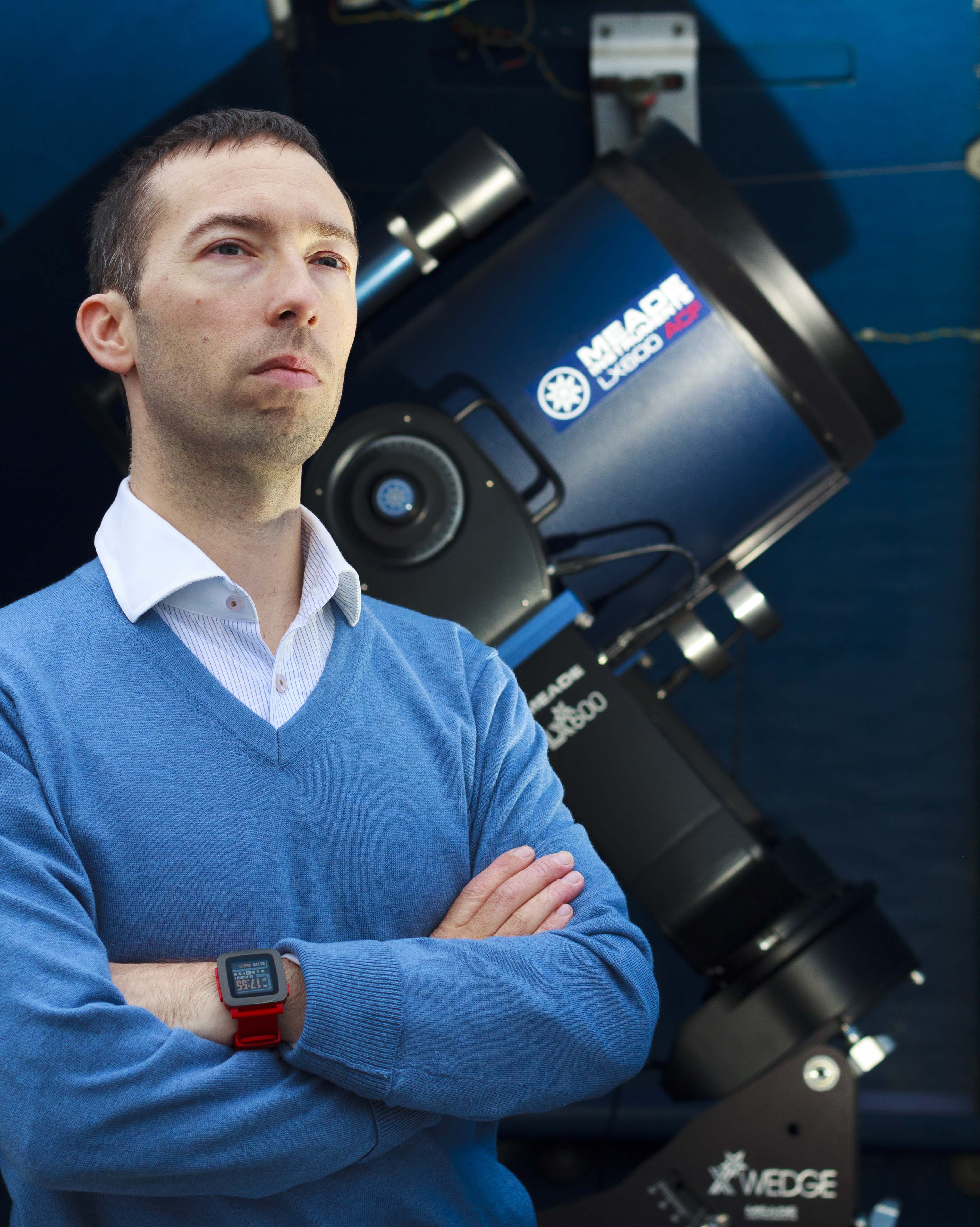 Dr. Adam Hill next to an optical telescope